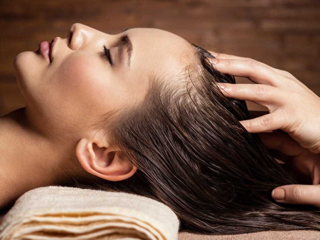 Woman receiving relaxing head massage while lying on towel in spa setting.