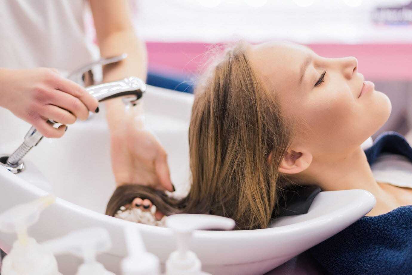Person enjoying a hair wash at a salon, reclining with eyes closed during the treatment.