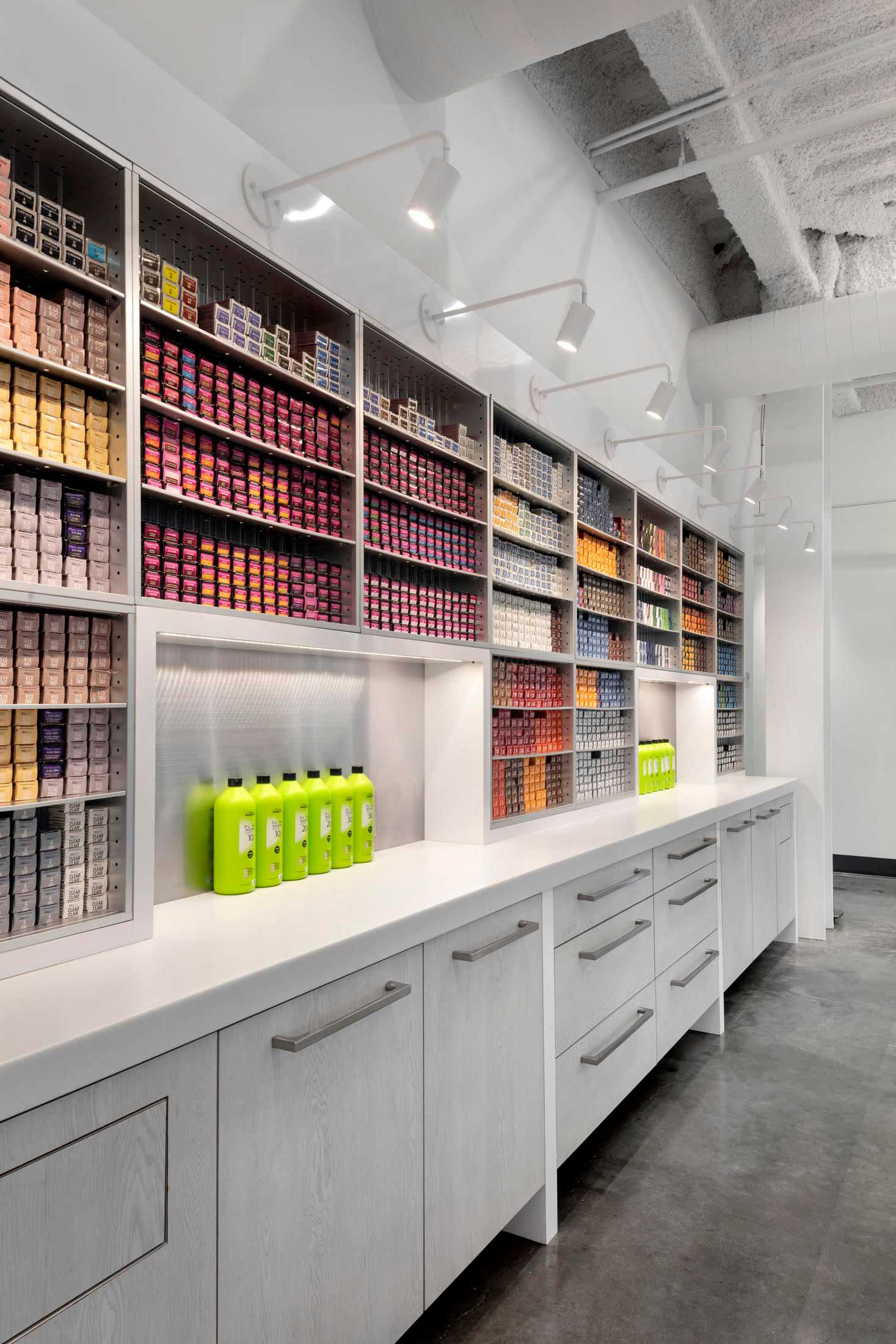 Modern hair salon storage with neatly organized hair color boxes on shelves and bright lighting.